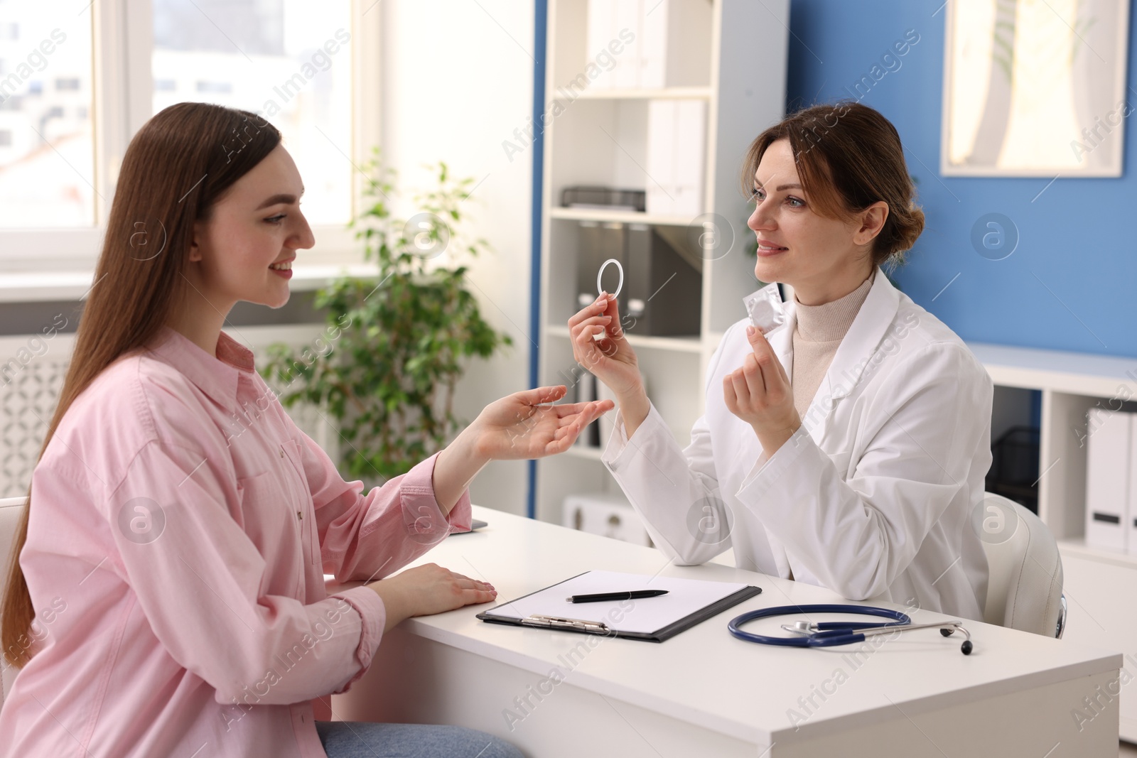 Photo of Gynecologist showing different contraceptive products to woman in clinic