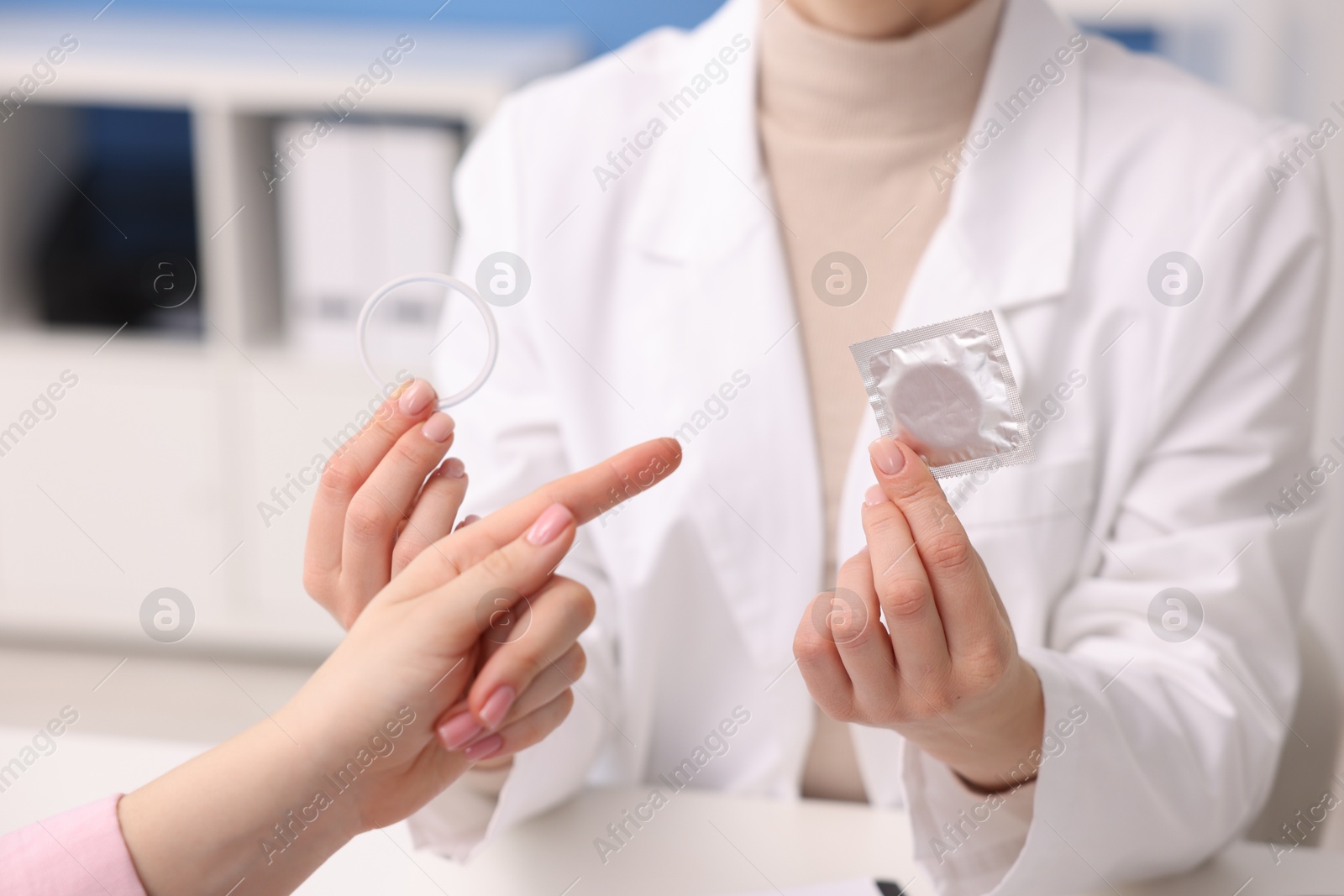 Photo of Gynecologist showing different contraceptive products to woman in clinic, closeup