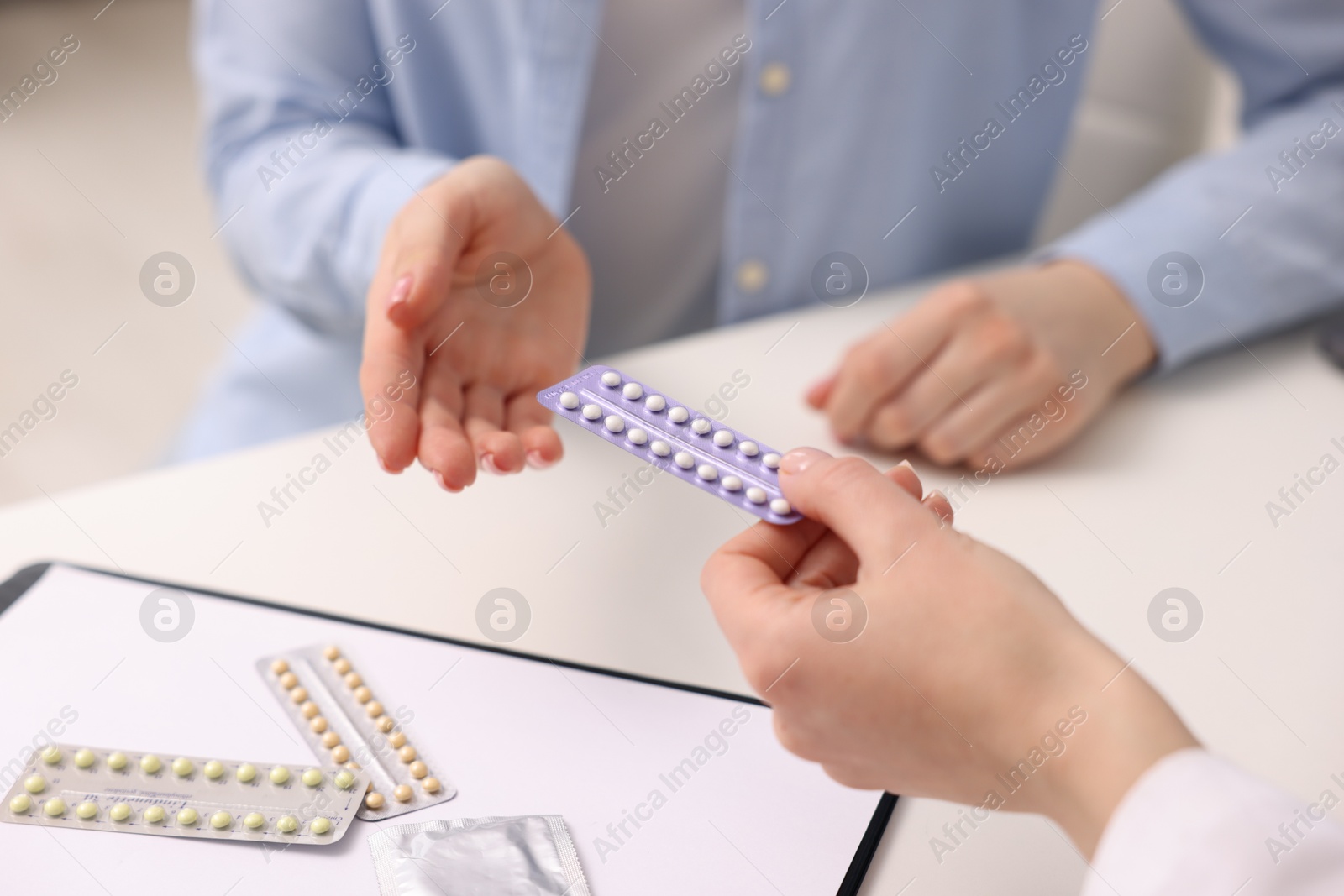 Photo of Gynecologist recommending contraceptive pills to woman in clinic, closeup