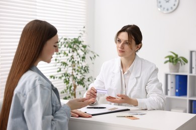 Gynecologist recommending contraceptive pills to woman in clinic