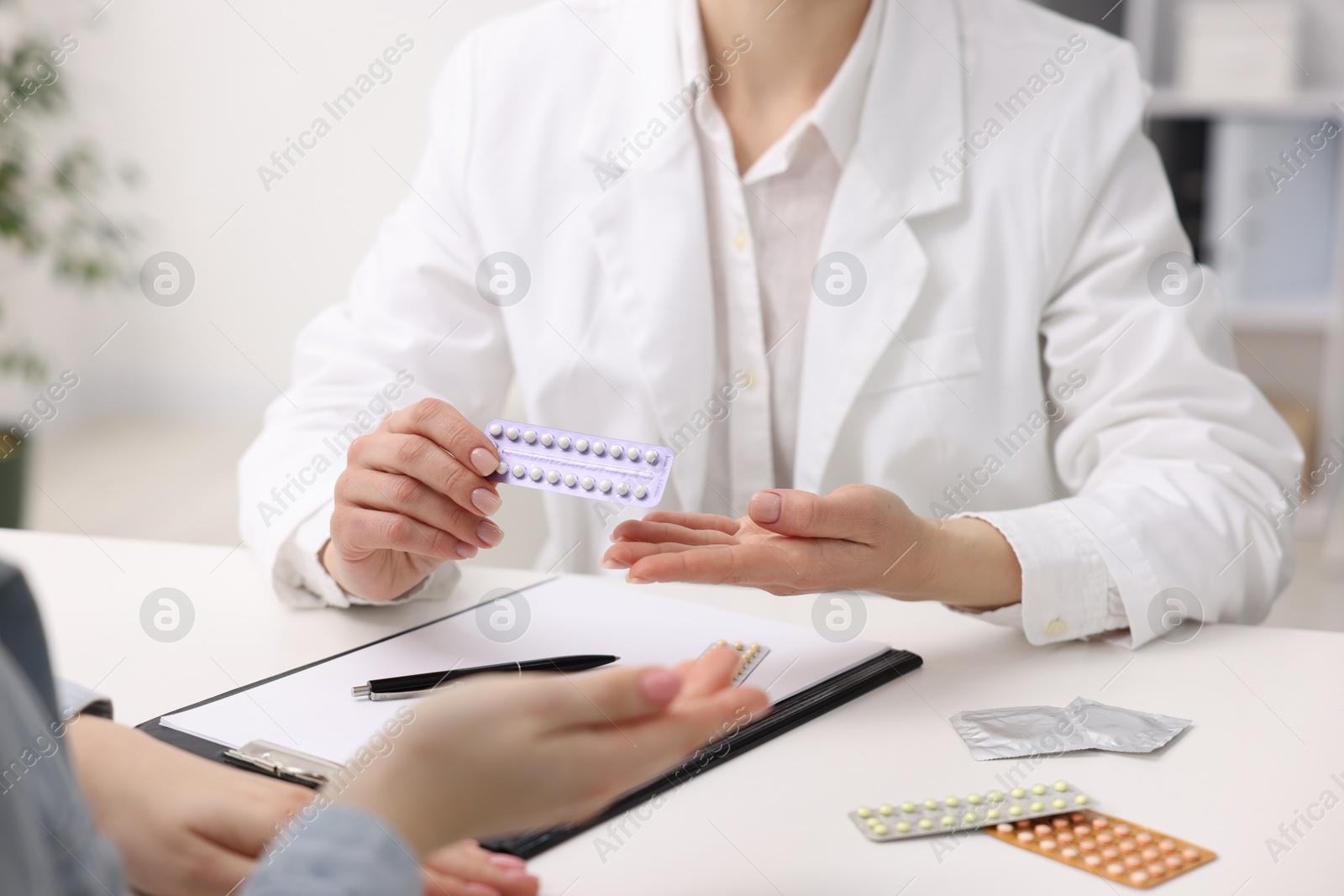 Photo of Gynecologist recommending contraceptive pills to woman in clinic, closeup