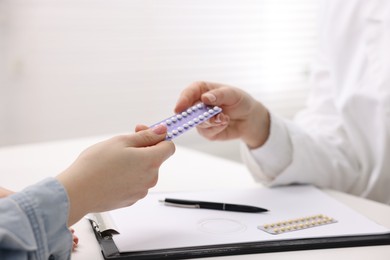 Photo of Gynecologist recommending contraceptive pills to woman in clinic, closeup