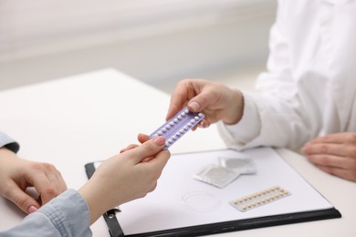 Photo of Gynecologist recommending contraceptive pills to woman in clinic, closeup