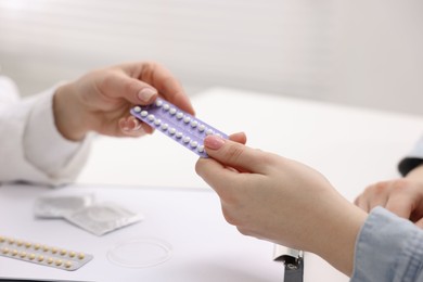 Photo of Gynecologist recommending contraceptive pills to woman in clinic, closeup