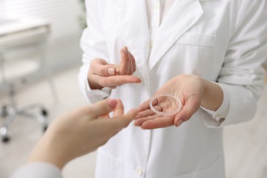 Contraception. Gynecologist recommending vaginal ring to woman in clinic, closeup