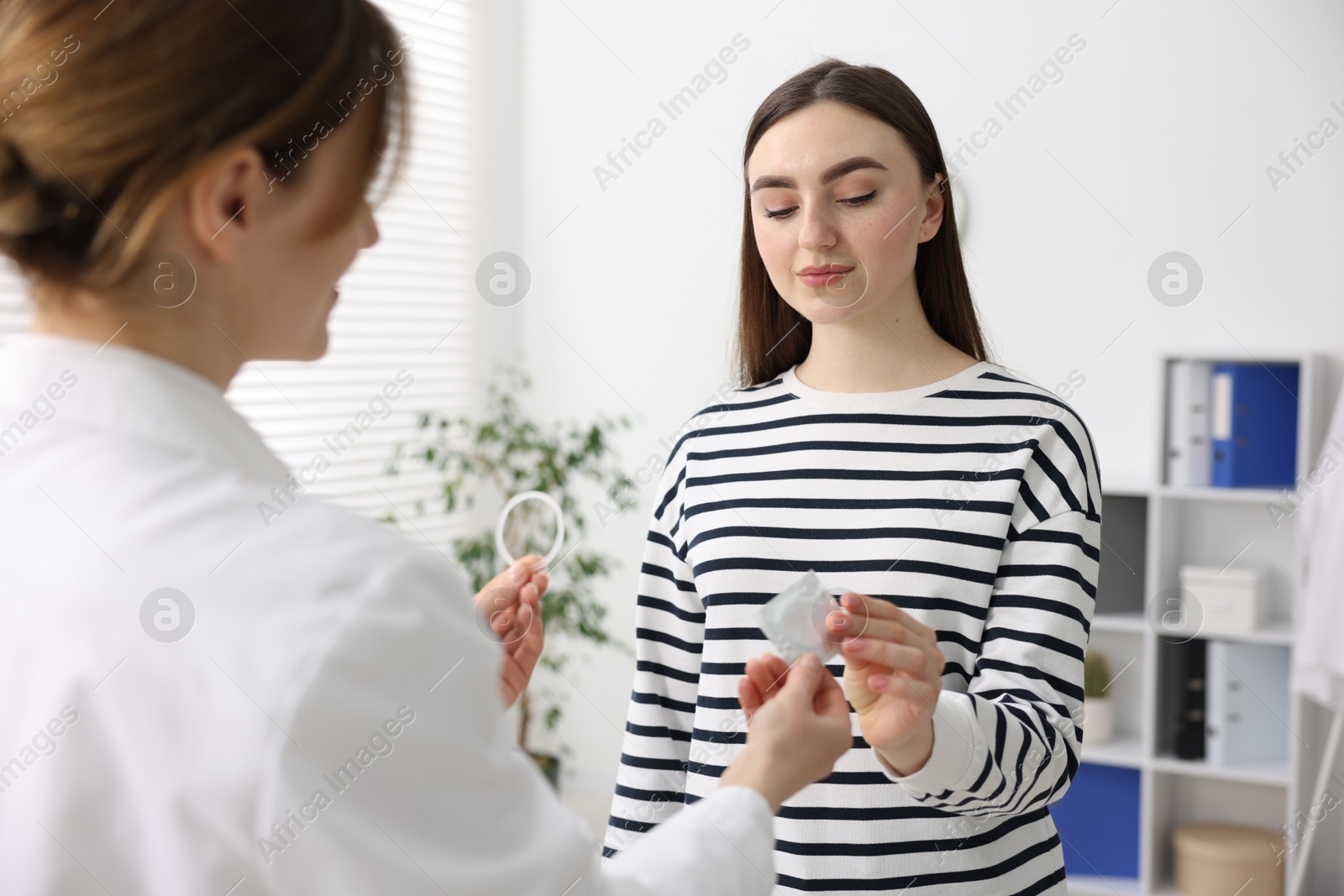 Photo of Gynecologist showing different contraceptive products to woman in clinic