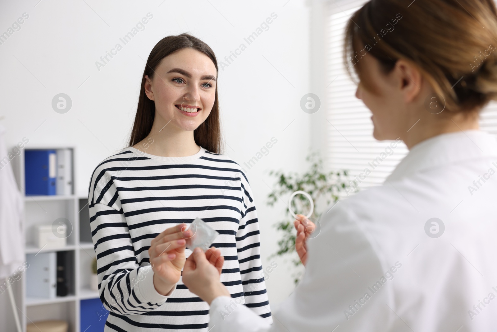 Photo of Gynecologist showing different contraceptive products to woman in clinic