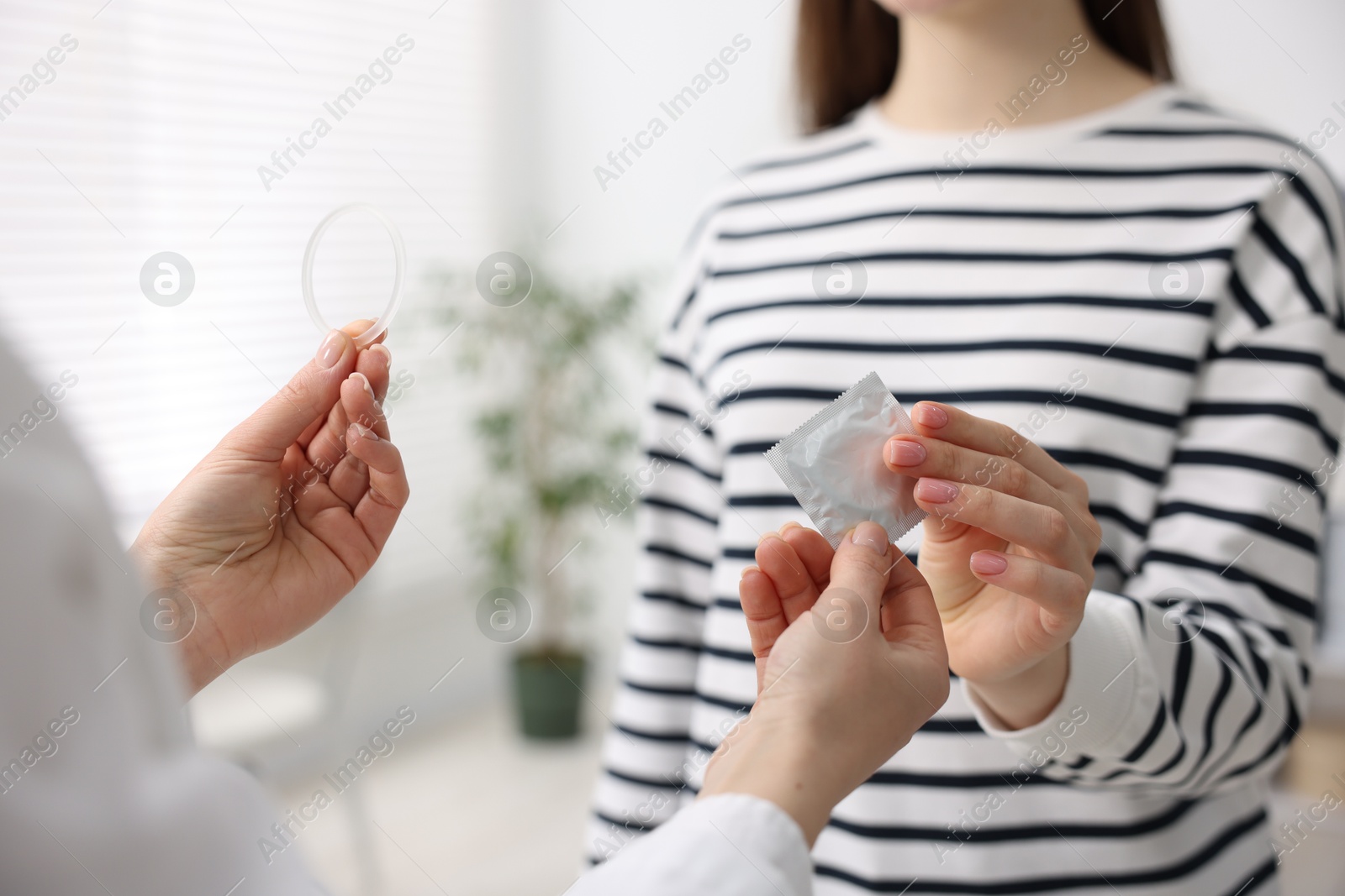 Photo of Gynecologist showing different contraceptive products to woman in clinic, closeup