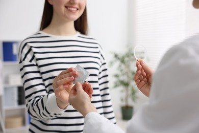 Gynecologist showing different contraceptive products to woman in clinic, closeup