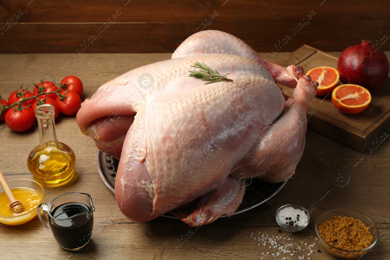 Photo of Whole raw turkey with ingredients on wooden table