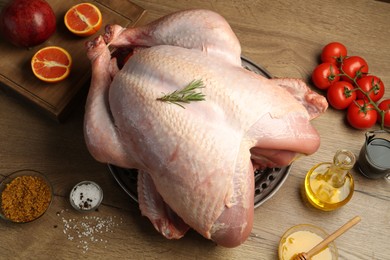 Photo of Whole raw turkey with ingredients on wooden table, flat lay