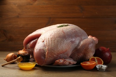 Photo of Whole raw turkey with ingredients on wooden table