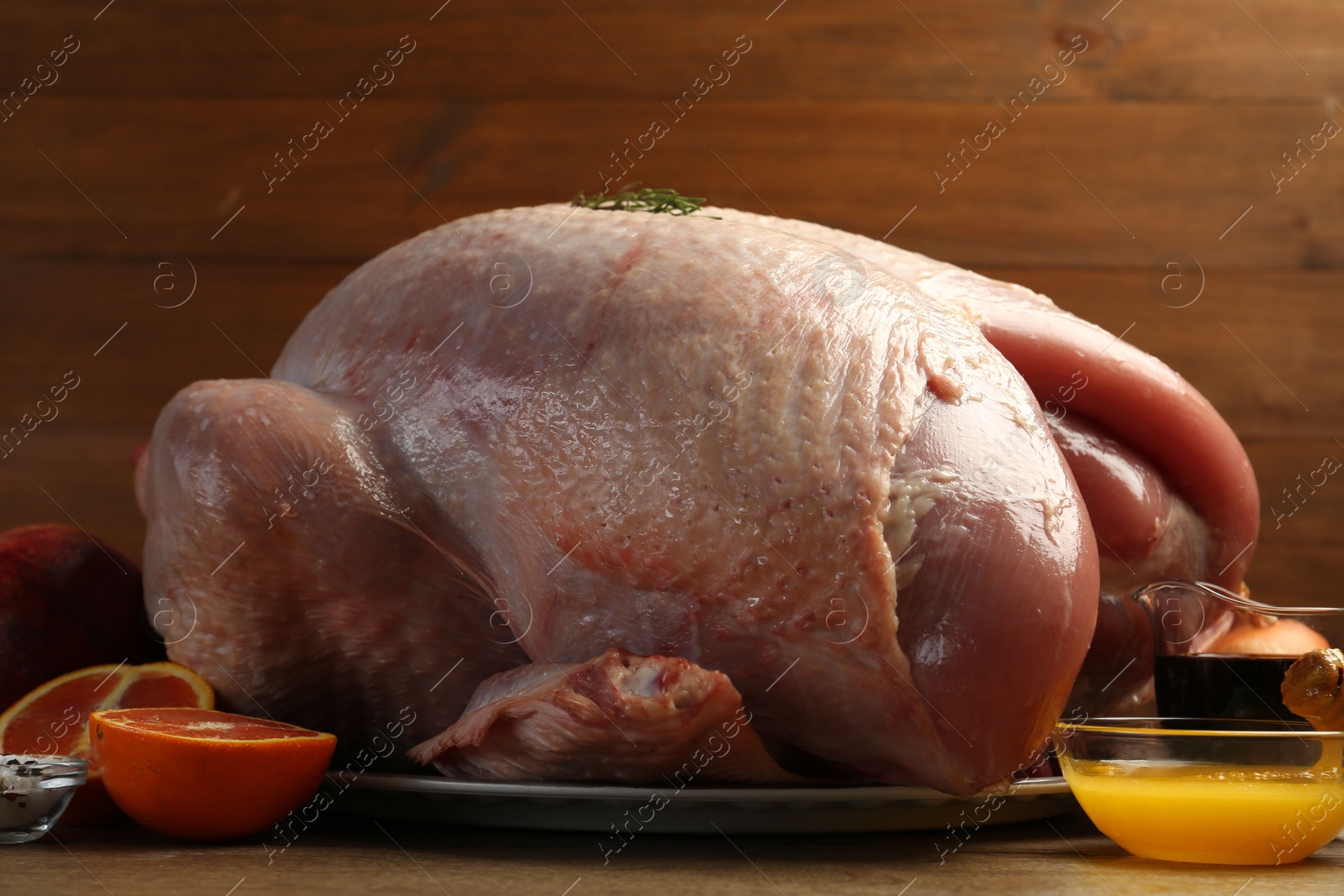 Photo of Whole raw turkey with ingredients on wooden table, closeup