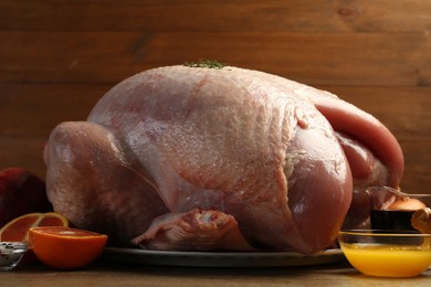 Photo of Whole raw turkey with ingredients on wooden table, closeup