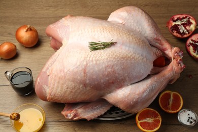 Photo of Whole raw turkey with ingredients on wooden table, above view