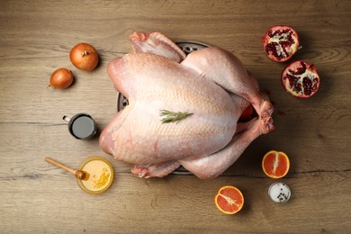 Photo of Whole raw turkey with ingredients on wooden table, flat lay