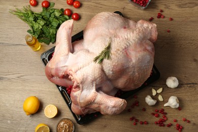 Photo of Whole raw turkey with ingredients for marinade on wooden table, flat lay