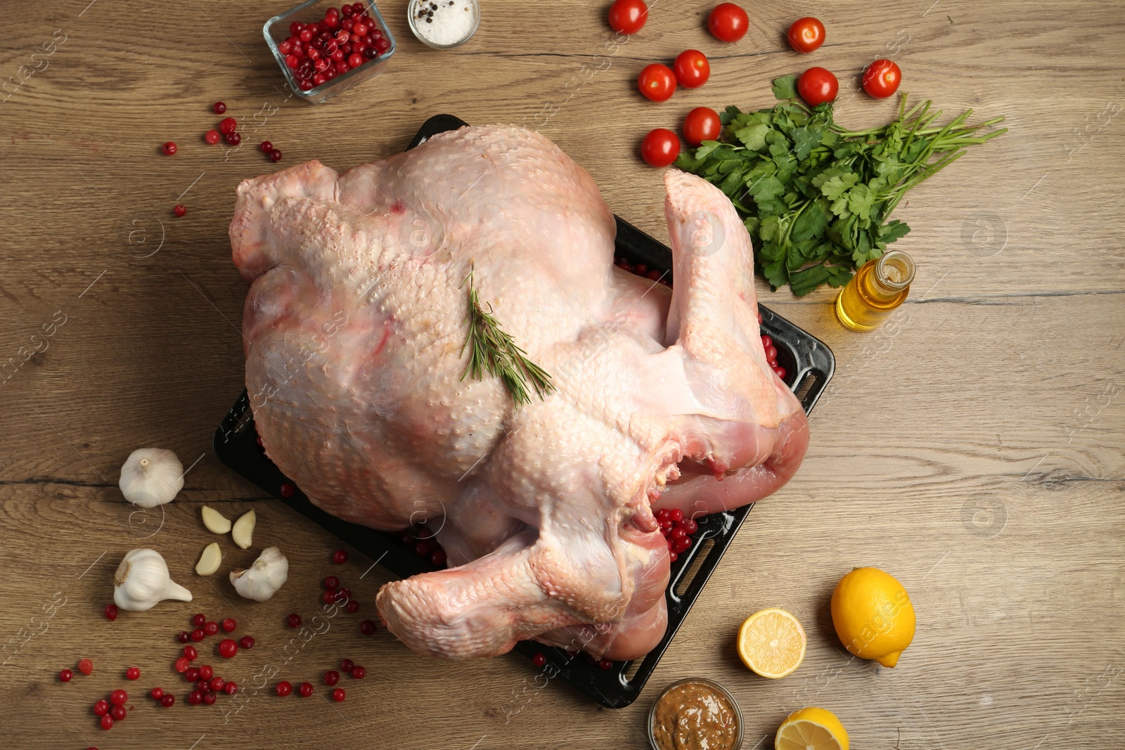 Photo of Whole raw turkey with ingredients for marinade on wooden table, flat lay