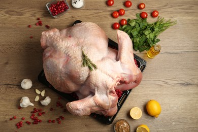 Photo of Whole raw turkey with ingredients for marinade on wooden table, flat lay