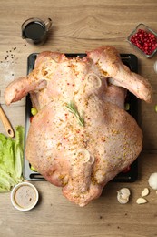 Photo of Whole raw turkey with ingredients for marinade on wooden table, flat lay