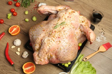 Photo of Whole raw turkey with ingredients for marinade on wooden table, above view