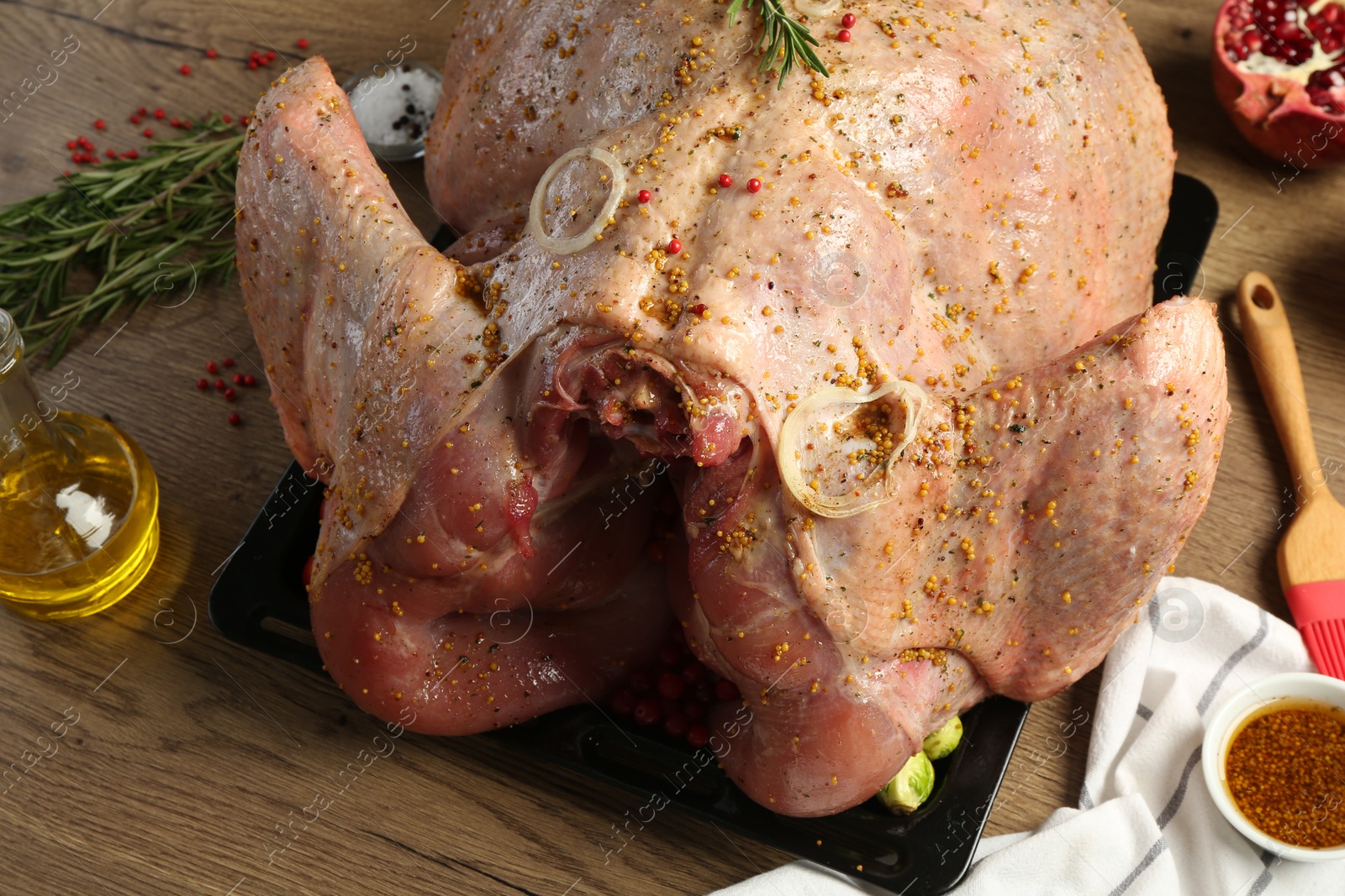 Photo of Whole raw turkey with ingredients for marinade on wooden table, closeup