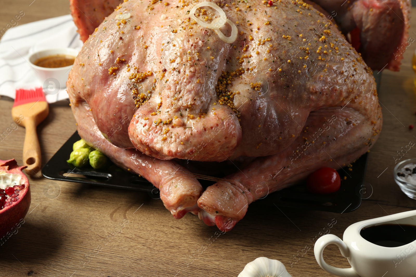 Photo of Whole raw turkey with ingredients for marinade on wooden table, closeup