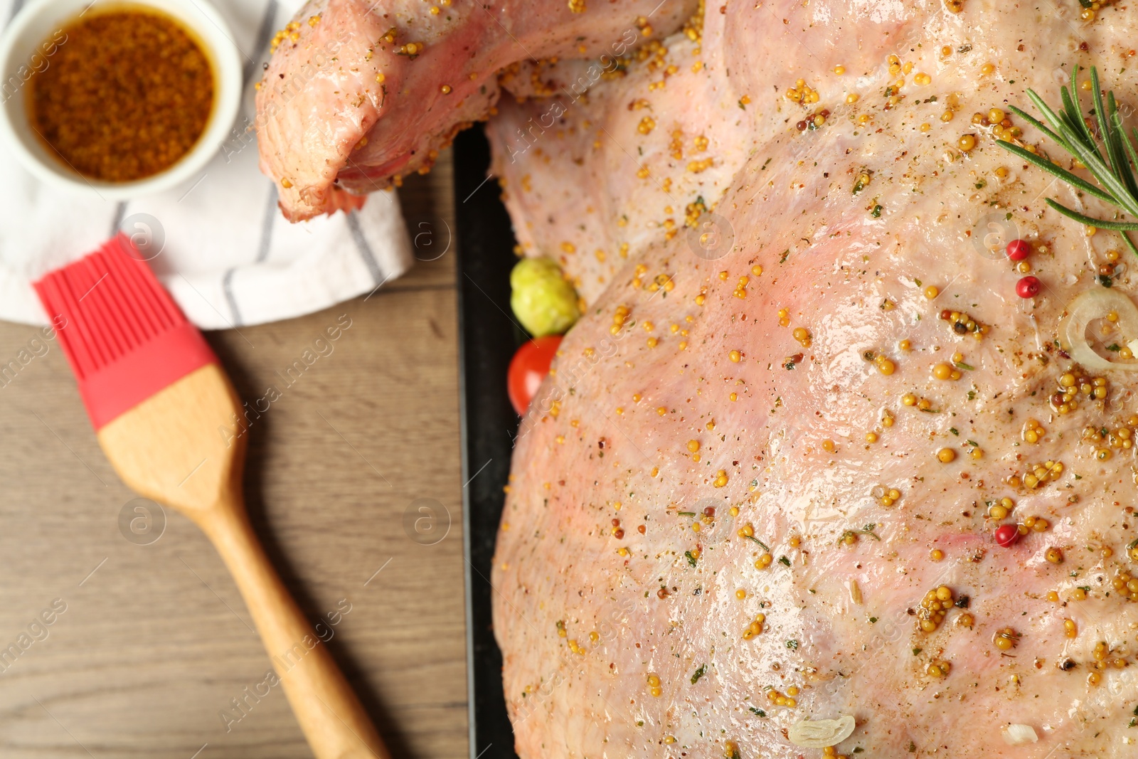 Photo of Whole raw turkey with marinade and basting brush on wooden table, above view