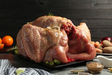 Photo of Whole raw turkey with ingredients for marinade and other products on grey table