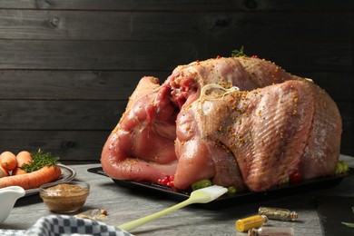 Photo of Whole raw turkey with ingredients for marinade and other products on grey table