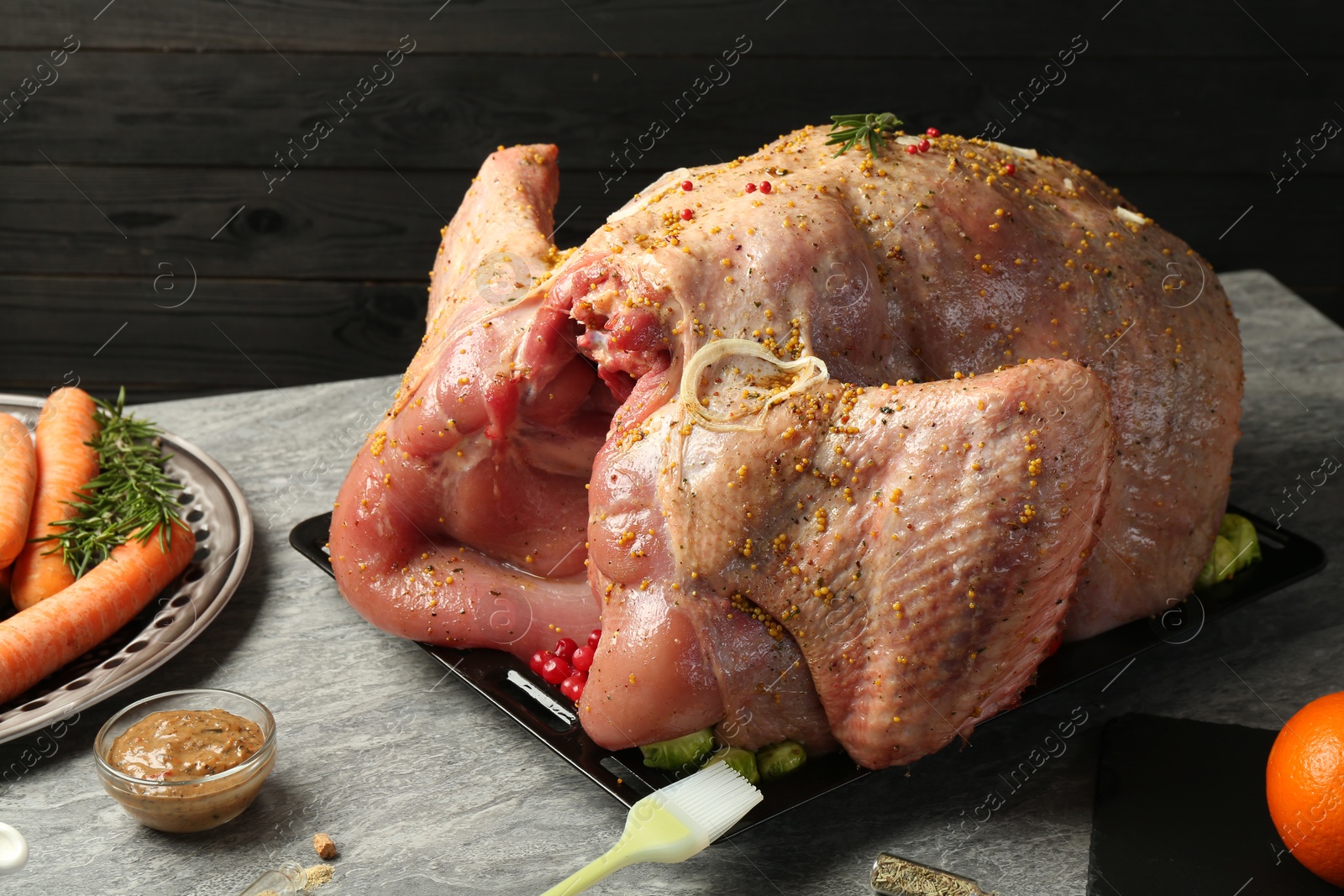 Photo of Whole raw turkey with ingredients for marinade and other products on grey table