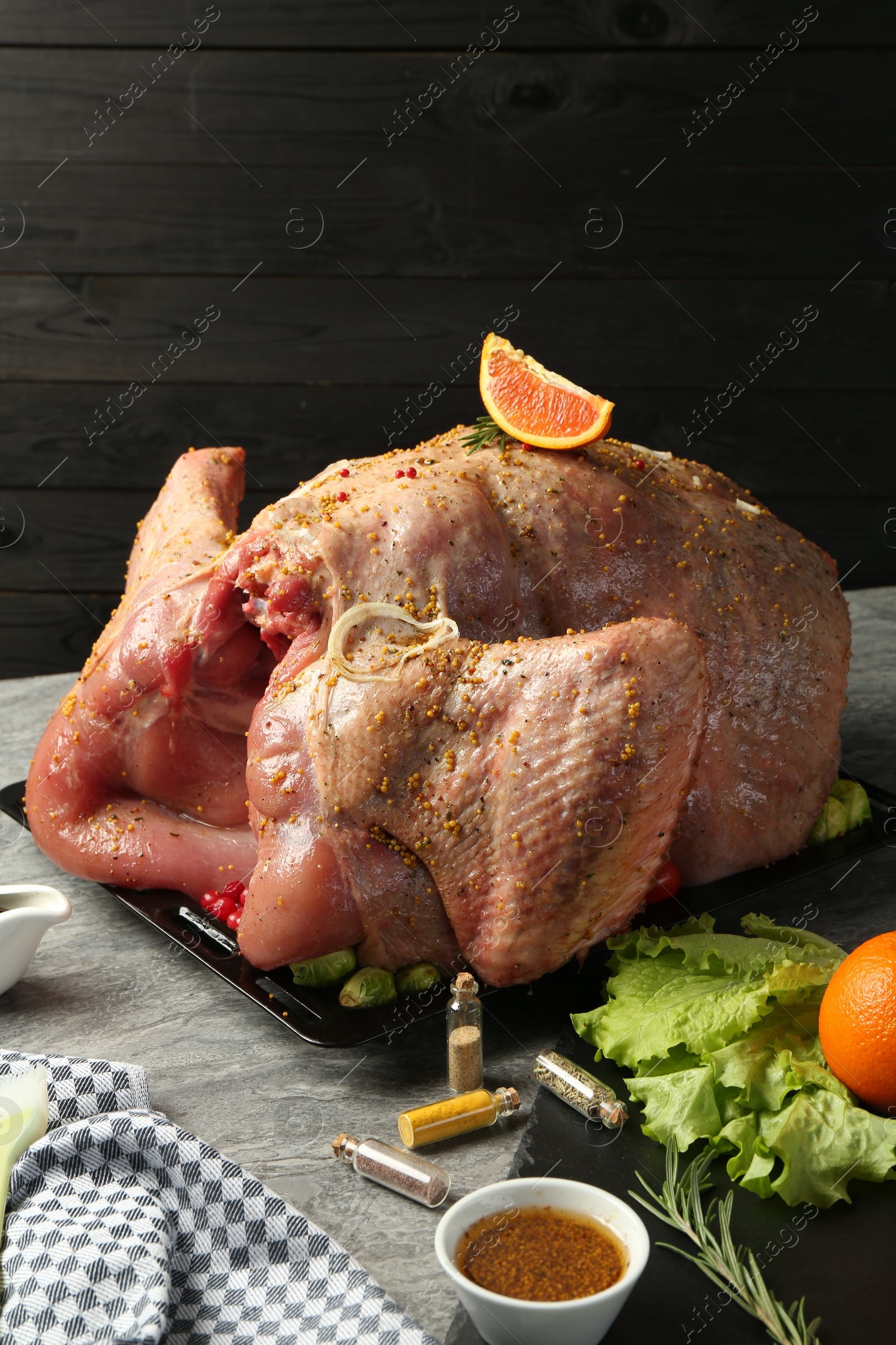 Photo of Whole raw turkey with ingredients for marinade and other products on grey table