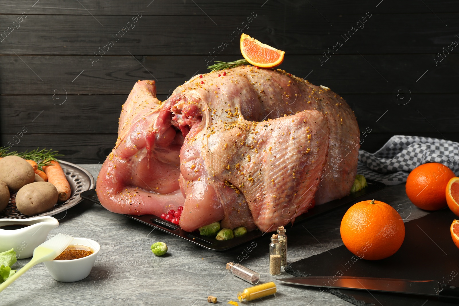 Photo of Whole raw turkey with ingredients for marinade and other products on grey table