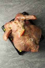 Photo of Whole raw turkey with marinade on grey table, top view