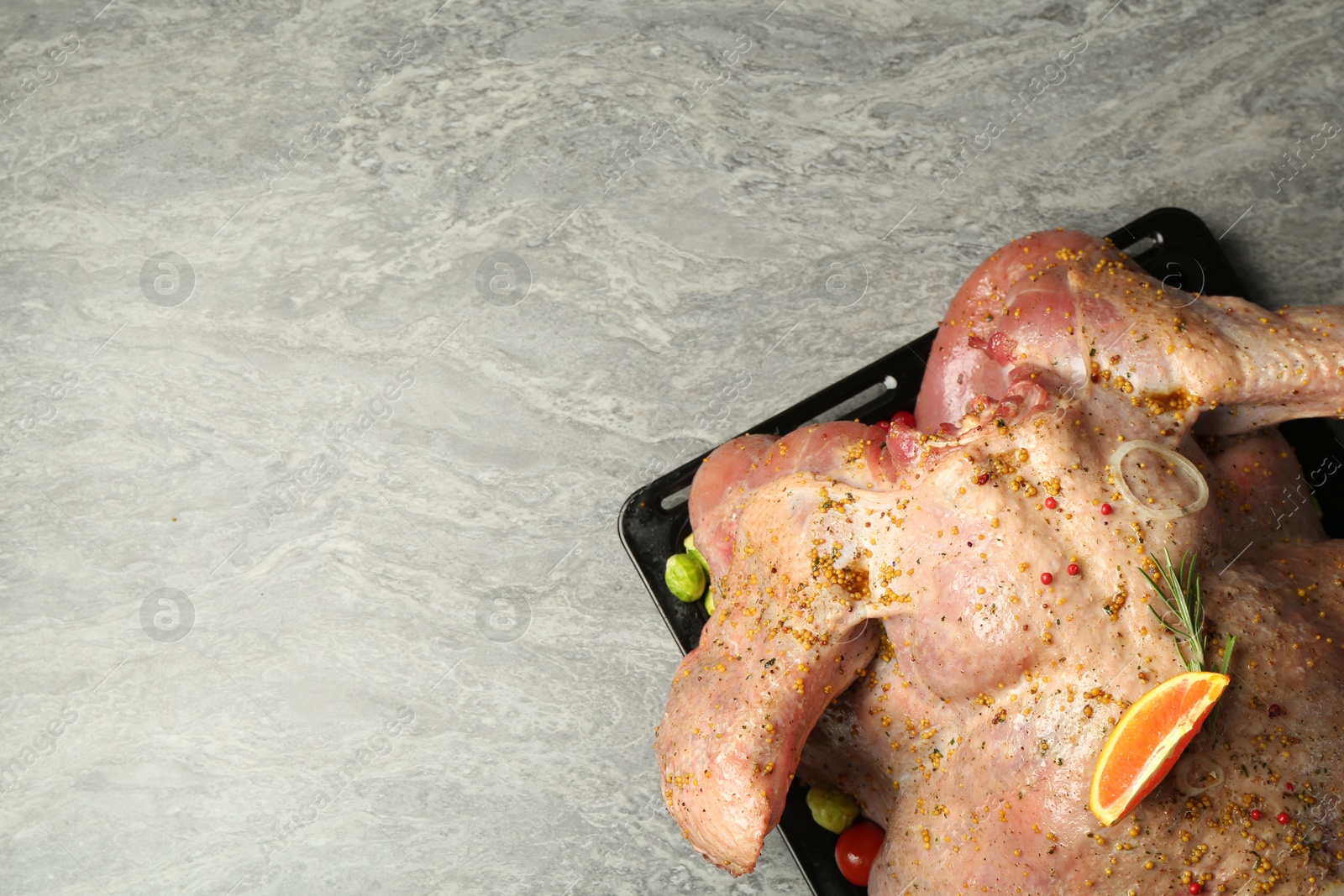 Photo of Whole raw turkey with marinade on grey table, top view. Space for text