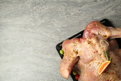 Photo of Whole raw turkey with marinade on grey table, top view. Space for text