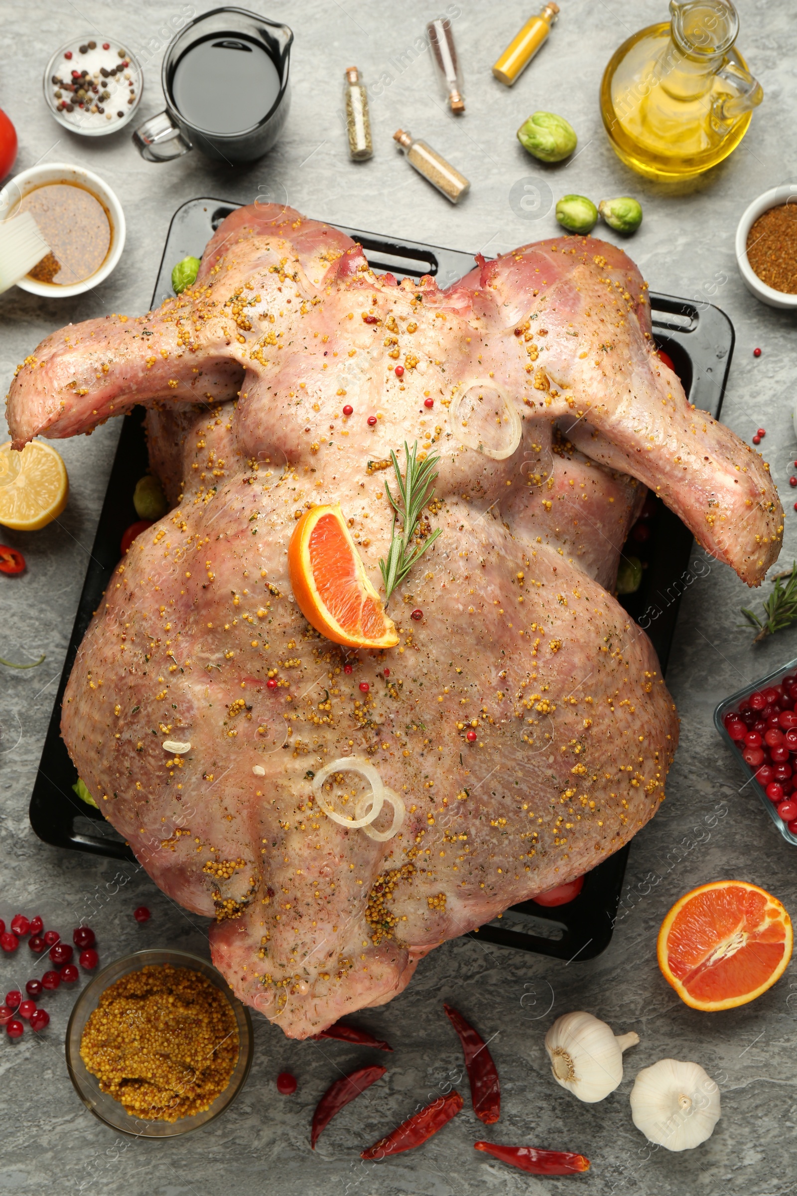 Photo of Whole raw turkey with ingredients for marinade on grey table, flat lay