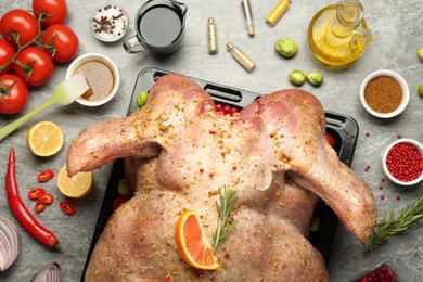 Photo of Whole raw turkey with ingredients for marinade on grey table, flat lay