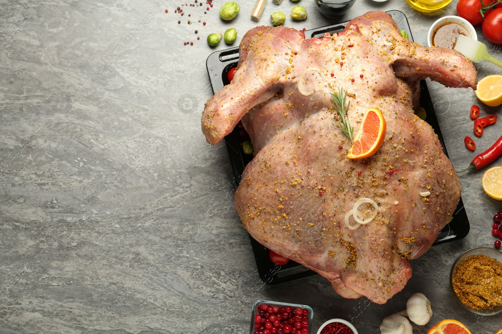 Photo of Whole raw turkey with ingredients for marinade on grey table, flat lay. Space for text