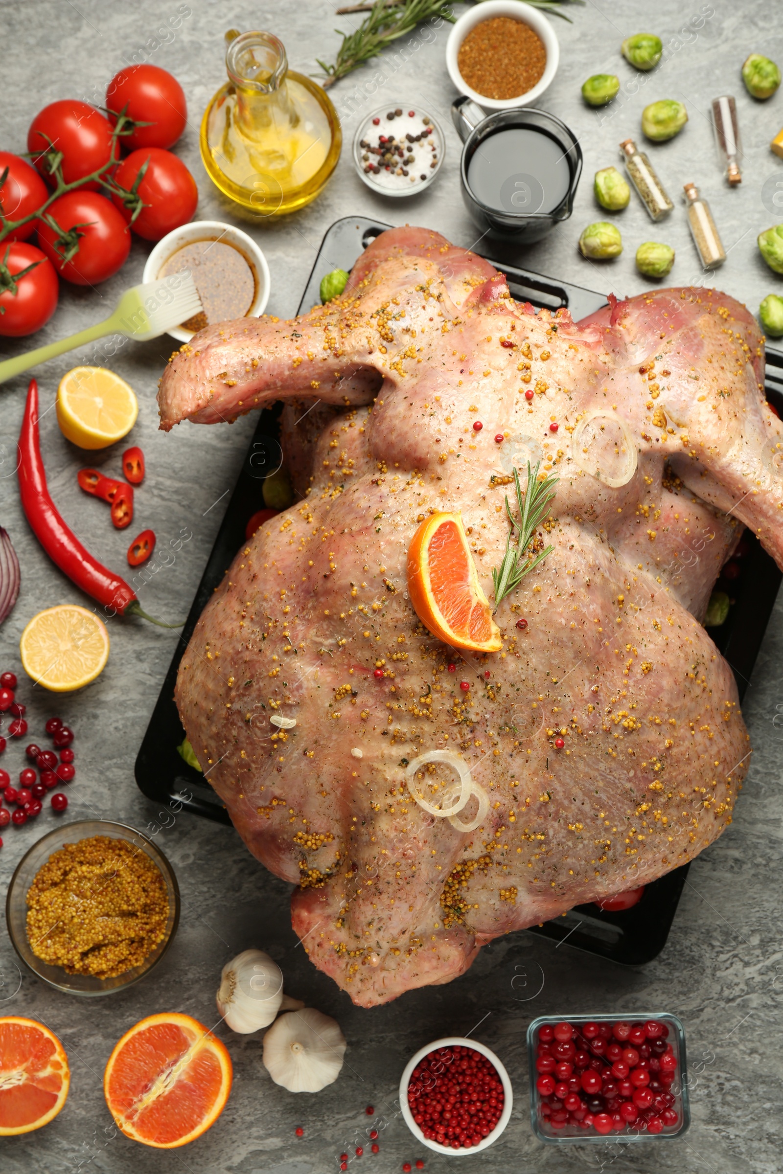 Photo of Whole raw turkey with ingredients for marinade on grey table, flat lay