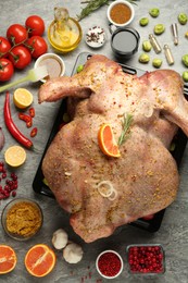 Whole raw turkey with ingredients for marinade on grey table, flat lay