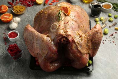 Photo of Whole raw turkey with ingredients for marinade on grey table, closeup