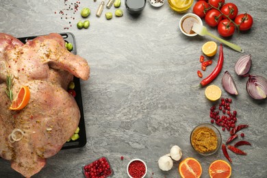 Photo of Frame of whole raw turkey with ingredients for marinade on grey table, flat lay. Space for text