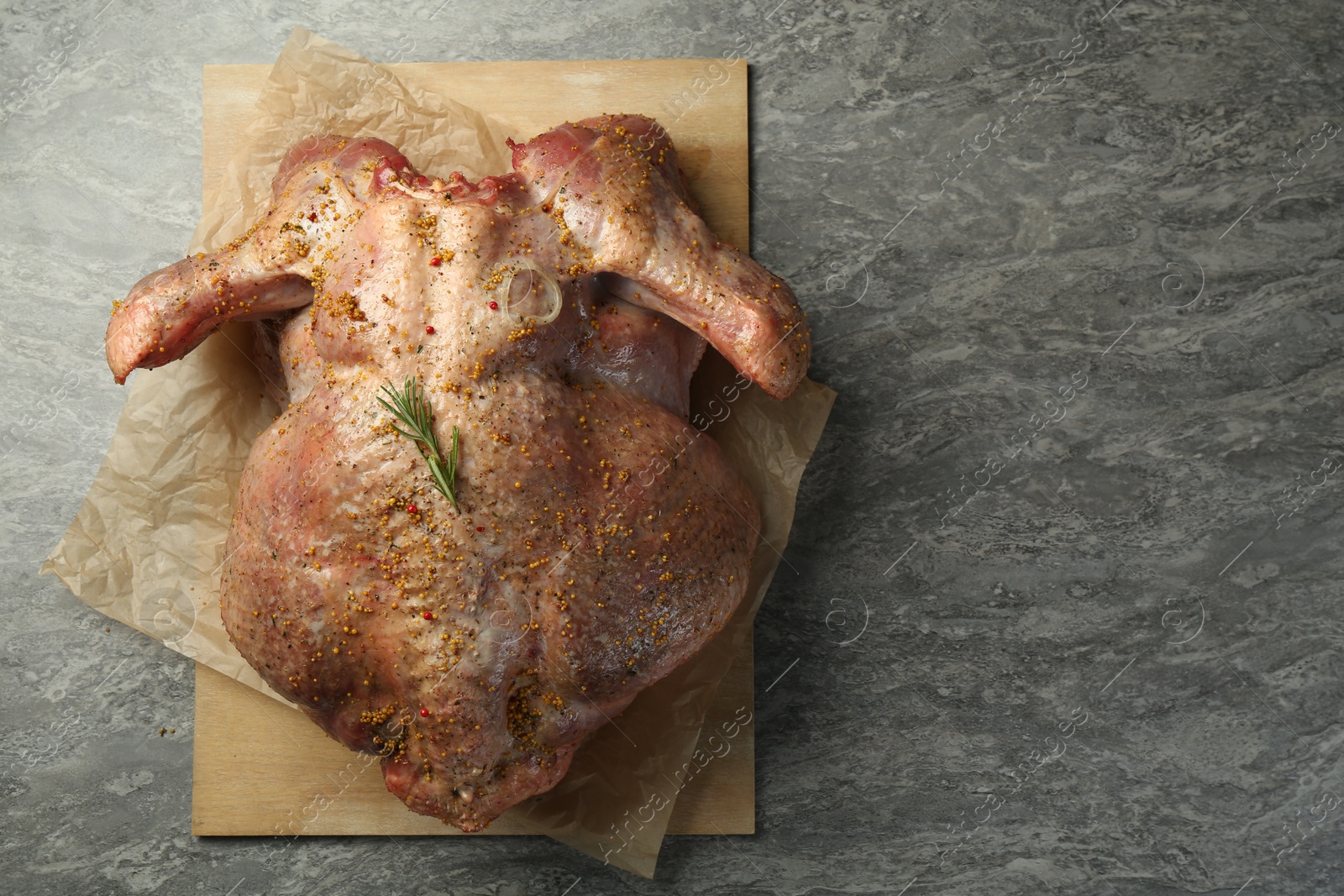 Photo of Whole raw turkey with spices on grey table, top view. Space for text