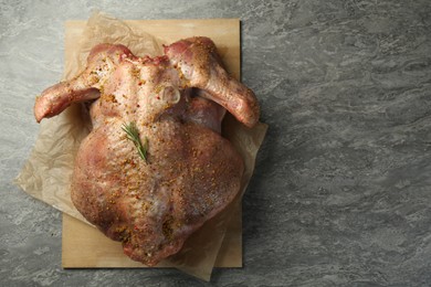 Photo of Whole raw turkey with spices on grey table, top view. Space for text