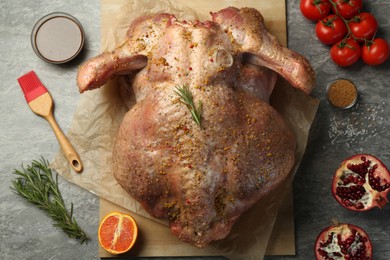 Photo of Whole raw turkey with ingredients for marinade on grey table, flat lay