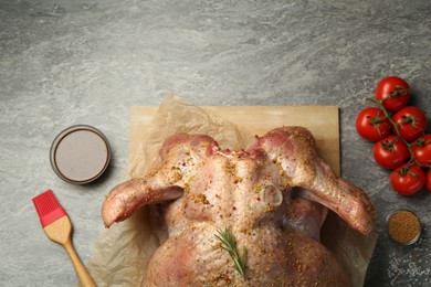 Photo of Whole raw turkey with ingredients for marinade on grey table, flat lay