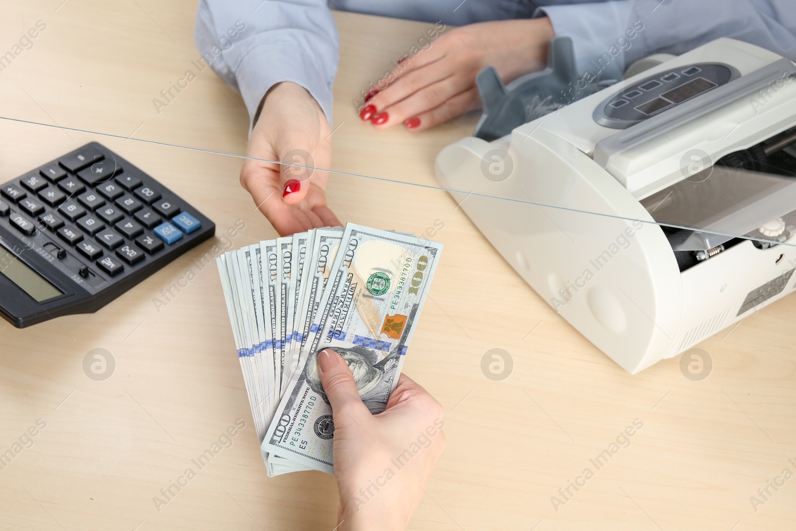 Photo of Client giving dollar banknotes to cashier at table in money exchange, closeup