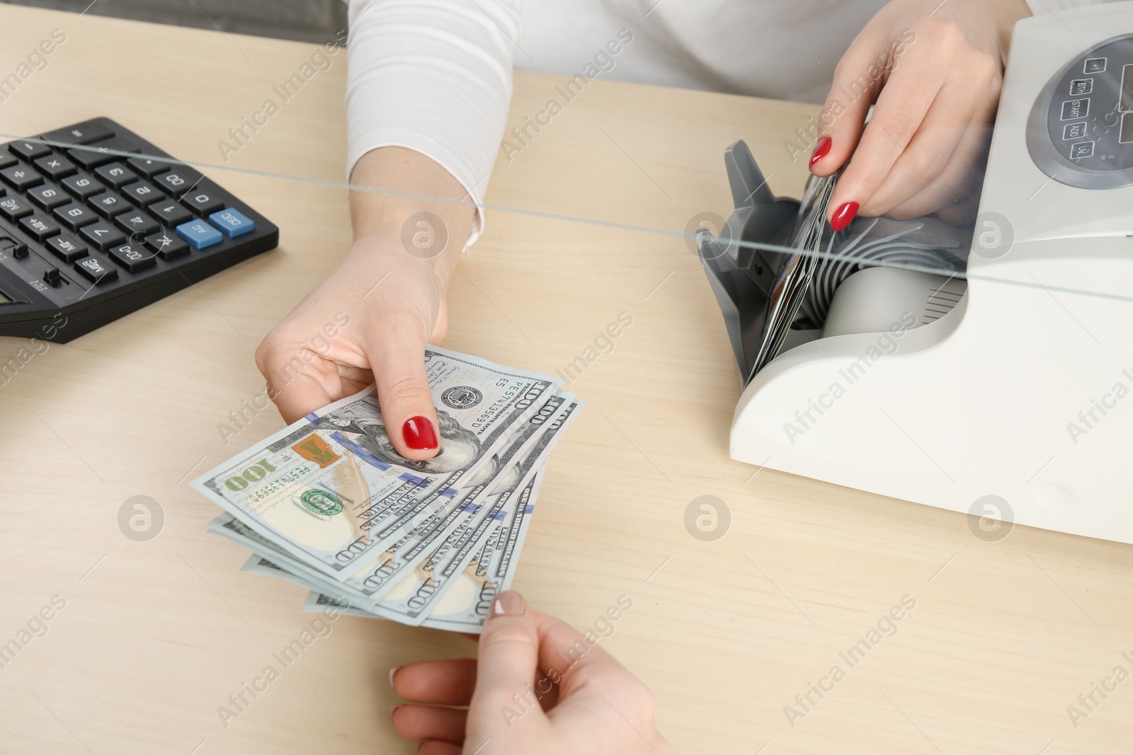 Photo of Cashier giving dollar banknotes to client at table in money exchange, closeup