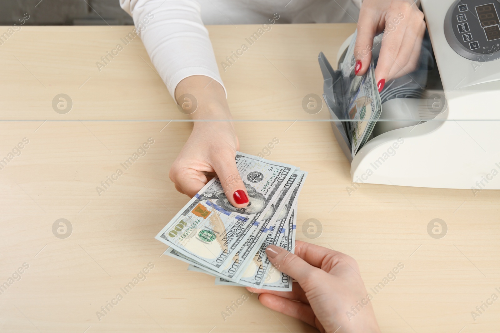 Photo of Cashier giving dollar banknotes to client at table in money exchange, closeup